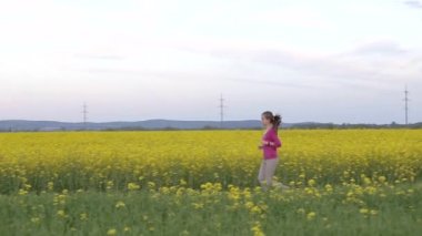 Çiçek açan tarlalarda koşan genç kadın.