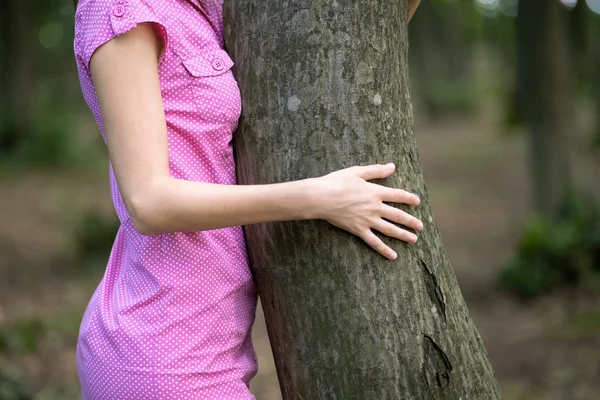 Młoda Kobieta Różowej Sukience Pochylająca Się Pnia Drzewa Przytulając Dłońmi — Zdjęcie stockowe