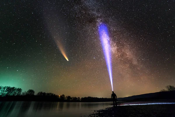 강둑에서 손전등을 남자가 어두운 밤하늘에 가벼운 꼬리를 밀키웨이 은하와 혜성에 — 스톡 사진