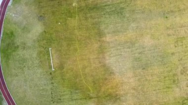 Yeşil çimenler ve su püskürten fıskiyelerle kaplı futbol sahası yüzeyinin yukarıdan görünüşü.