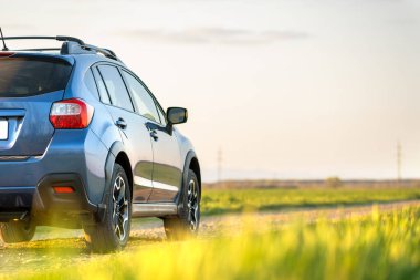 Çakıl yolunda mavi off-road arabalı manzara. Otomobille seyahat, vahşi yaşam macerası, keşif gezisi ya da bir SUV otomobili ile aşırı seyahat. Offroad 4x4 aracı gün doğumunda arazide olacak..