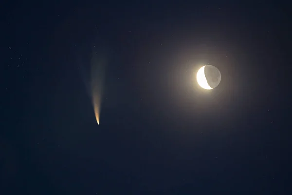 Night blue sky with bright moon and C/2020 F3 (NEOWISE) comet with light tail.