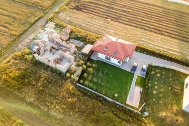 İki özel evin yukarıdan aşağı görüntüsü, biri beton temeli ve tuğla duvarlı, diğeri de kırmızı kiremitli çatıyla bitirilmiş..