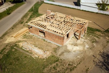 İnşaat halindeki ahşap çatı iskeleti olan bitmemiş tuğla evin havadan görüntüsü..