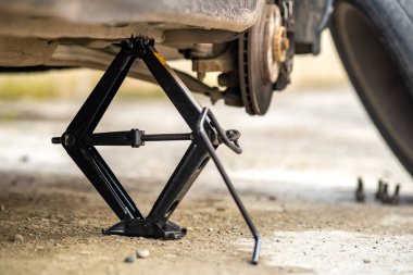 Jack 'in yeni tekerlek değiştirme işlemi sırasında kaldırdığı arabanın yakınlaştırılması. Sokakta bir aracın bozulması.