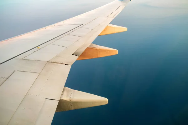 Stock image View from airplane on the aircraft white wing flying over ocean landscape in sunny morning. Air travel and transportation concept.