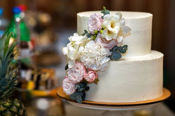 テーブルの上にピンクと白の花で飾られた背の高い甘い結婚式のケーキ — ストック写真