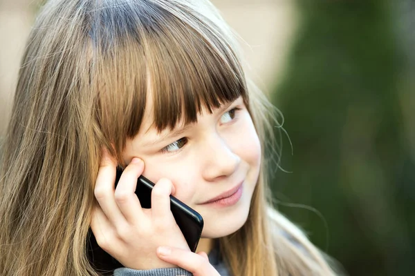 携帯電話で長い髪の少女の肖像画 小さな女性の子供がスマートフォンを使って通信しています 子どものコミュニケーションコンセプト — ストック写真