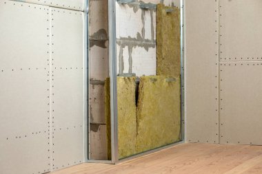 Alçıpan levhaları için hazırlanmış mineral kaya yünü yalıtımı ve metal iskeleti olan yenilenmiş bir odanın duvarı..