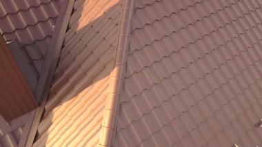 Kahverengi metal kiremitlerle kaplı evin çatı yapısının havadan görünüşü.