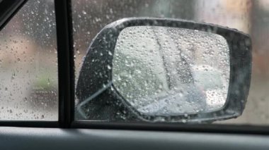 Dikiz aynasına yakın, yağmur damlaları arabanın ön camına düşüyor..