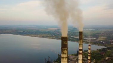 Kömür santralinden gelen gri dumanlı yüksek baca borularının havadan görüntüsü. Fosil yakıtla elektrik üretimi.