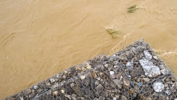 由卵石和金属网构成的潮汐侵蚀和防洪屏障 暴雨期间用泥水加固河流堤岸 — 图库视频影像