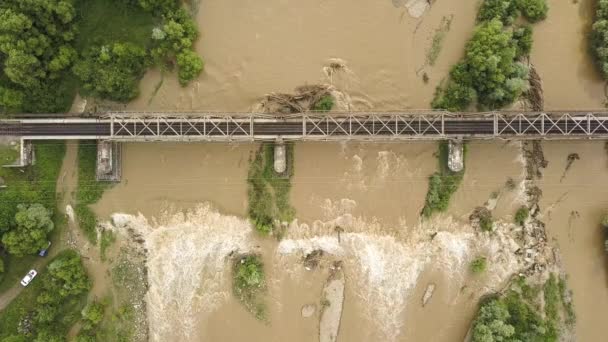 春の大雨による洪水期の濁った川にかかる鉄道用金属製橋の空中写真 — ストック動画
