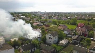 Turuncu alevler ve dumanla yanan bir evin havadan görünüşü.
