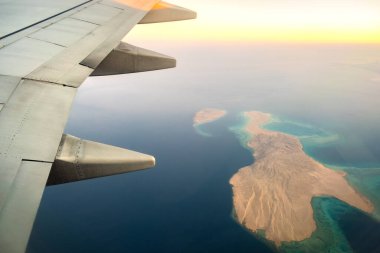 Güneşli bir sabahta, beyaz kanatlı uçaktan okyanus manzarasının üzerinden uçuşu. Hava yolculuğu ve ulaşım kavramı.