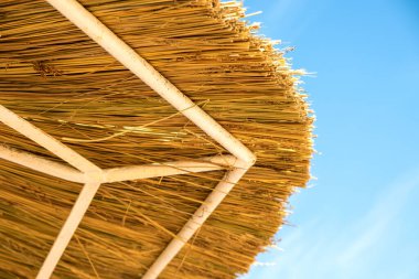 Mavi gökyüzüne karşı sarı saman çatının detaylarını kapat.