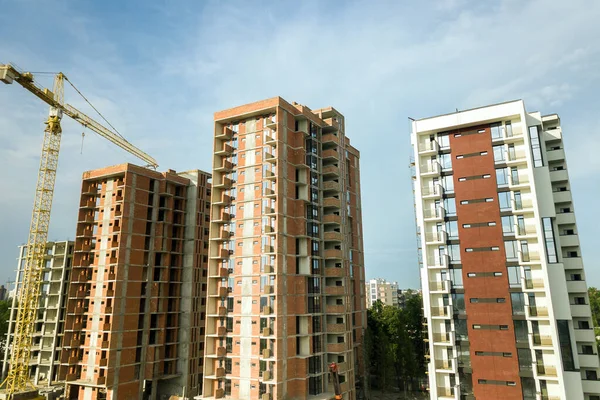 High-rise residential apartment buildings and tower crane under development on construction site. Real estate development.