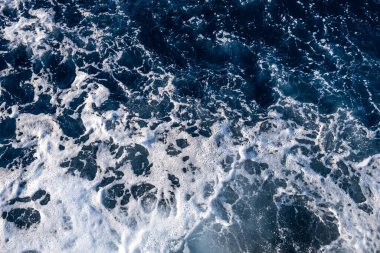 Deniz suyu yüzeyinin yukarıdan aşağıya doğru görüntüsü. Doğal arkaplan olarak beyaz köpük dalgaları dokusu.
