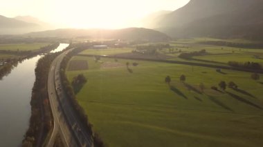 Yeşil tarlalar ve Alpler dağları arasındaki kırsal alanda hızlı giden otoyol manzaralı..