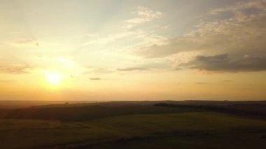 Baharda tarlaların üzerinde koyu sarı günbatımının havadan görünüşü.