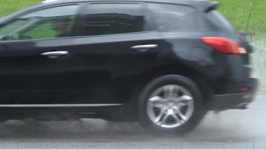 Arabalar hızlı gidiyor. Su basmış yollara kirli yağmur suyu püskürtüyor..