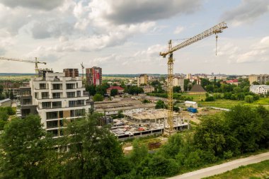 Kule görüntüsü, vinç kaldırma ve inşaat halindeki uzun apartmanın beton iskeleti. Kentsel kalkınma ve gayrimenkul büyüme kavramı.