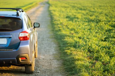 Çakıl yolunda mavi off-road arabalı manzara. Otomobille seyahat, vahşi yaşam macerası, keşif gezisi ya da bir SUV otomobili ile aşırı seyahat. Offroad 4x4 aracı gün doğumunda arazide olacak..