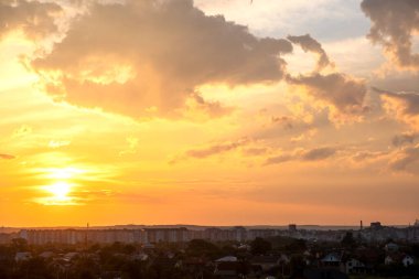 Turuncu batan güneş ve mavi gökyüzü tarafından aydınlatılan kabarık bulutlarla dramatik günbatımı kırsal manzarası.