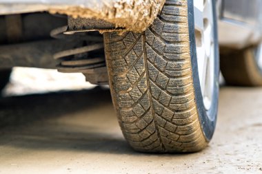 Lastik lastikli, sarı çamurla kaplı kirli araba tekerleğini kapat..