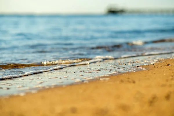 夏の晴れた海岸で黄色の砂のビーチの上に澄んだ青い水と小さな海の波の終わり — ストック写真