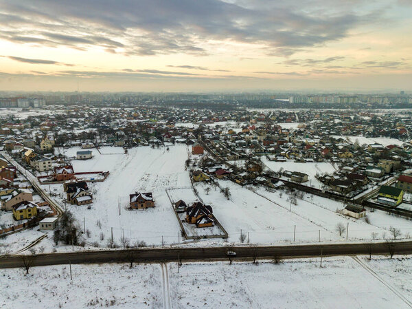 Top view of city suburbs or small town nice houses on winter morning on cloudy sky background. Aerial drone photography concept.