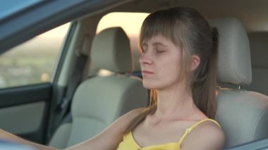Genç bayan sürücü arabasının direksiyonunda dinleniyor..