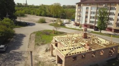 İnşaat halindeki ahşap çatı iskeleti olan bitmemiş tuğla evin havadan görüntüsü..