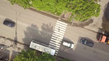 Yürüyen arabaları ve yaya geçitleri olan zebra yaya geçidi olan caddenin aşağı havadan görünüşü.