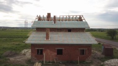 Ahşap çatı iskeleti olan tuğladan bir evin havadan görünüşü.