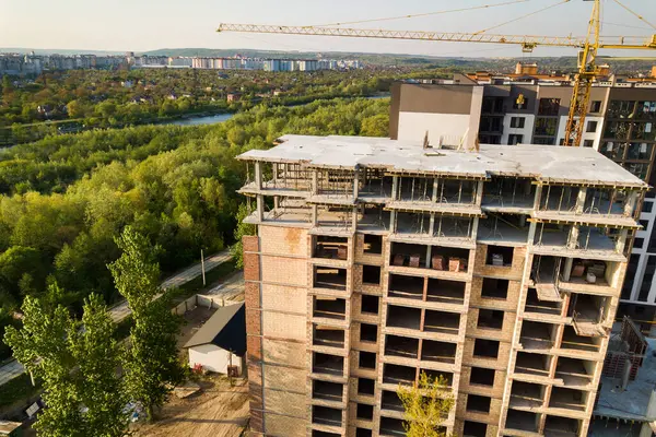 High multi storey residential apartment building under construction. Concrete and brick framing of high rise housing. Real estate development in urban area.