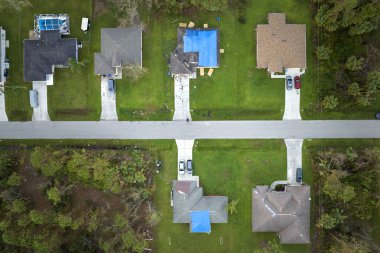 Asfalt kiremitlerin yerine konana kadar yağmur suyu sızıntılarına karşı koruyucu branda örtüleriyle kaplı çatı sızdırma manzarası. Florida 'daki Ian Kasırgası' nın yol açtığı çatı hasarı.