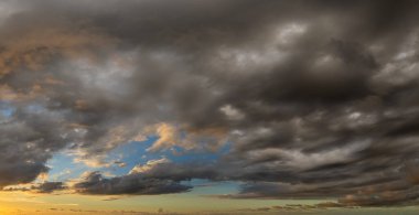 Parlak günbatımı, parlak turuncu ve sarı bulutların ardında batan güneş..