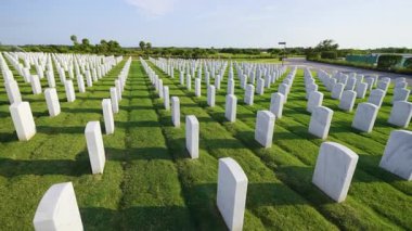 Yeşil çimlerin üzerinde beyaz mezar taşları olan Amerikan ulusal mezarlığı. Anma Günü konsepti