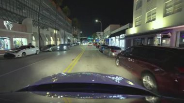Gece Miami Beach, Florida 'da araba kullanırken görülmüş. Ulaşım ve trafik kavramı. Şehir caddesinde güney binaları arasında araç sürüyor.