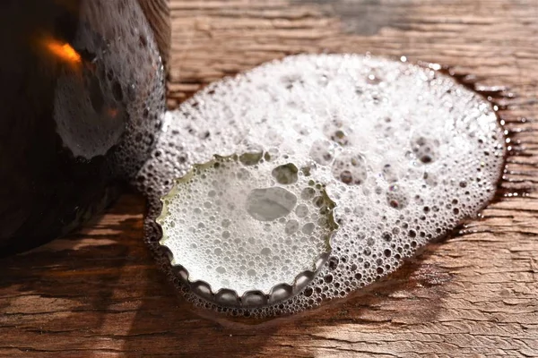 beer bottle cap with foam on wood table