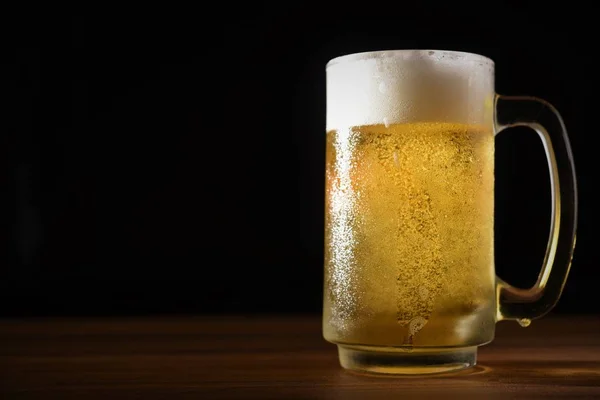 mug of beer on wood table dark background