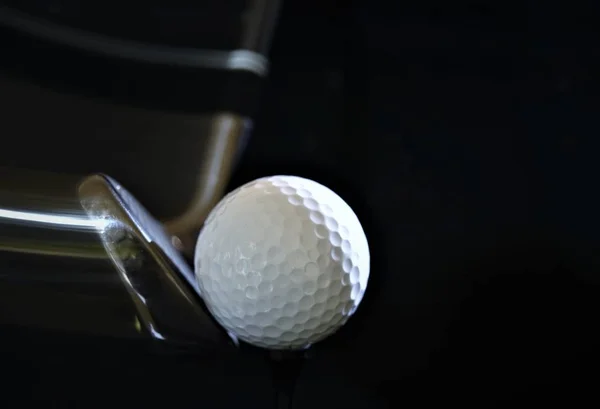 golf ball and golf club with trail behind on black background