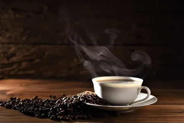 Gorąca Filiżanka Kawy Dymem Ziaren Kawy Drewnianym Stole Ciemne Tło — Zdjęcie stockowe