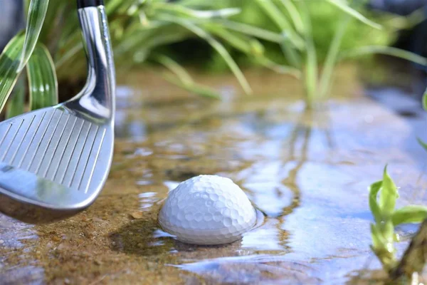 golf ball in water hazard with iron club head