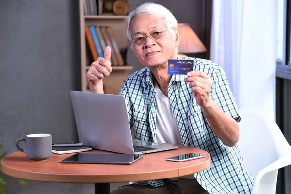 an old man happy with credit card and computer