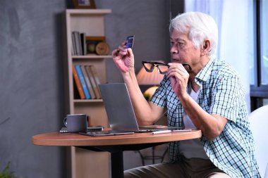 dizüstü bilgisayar ve kredi kartı ile çalışan yaşlı adam