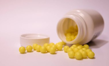 Beyaz kavanozdan çıkan sarı vitamin hapları