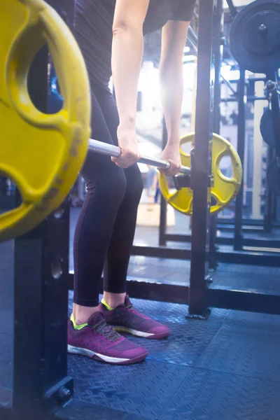 woman with a barbell doing exercises in the gym